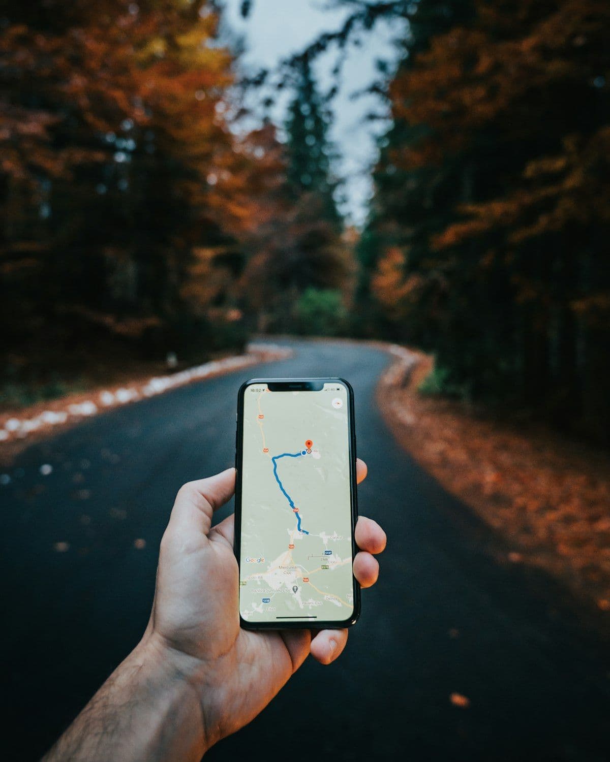Main tenant un smartphone affichant Google Maps avec un itineraire et des epingles de localisation, illustration des recherches locales mobiles dans les Hautes-Alpes