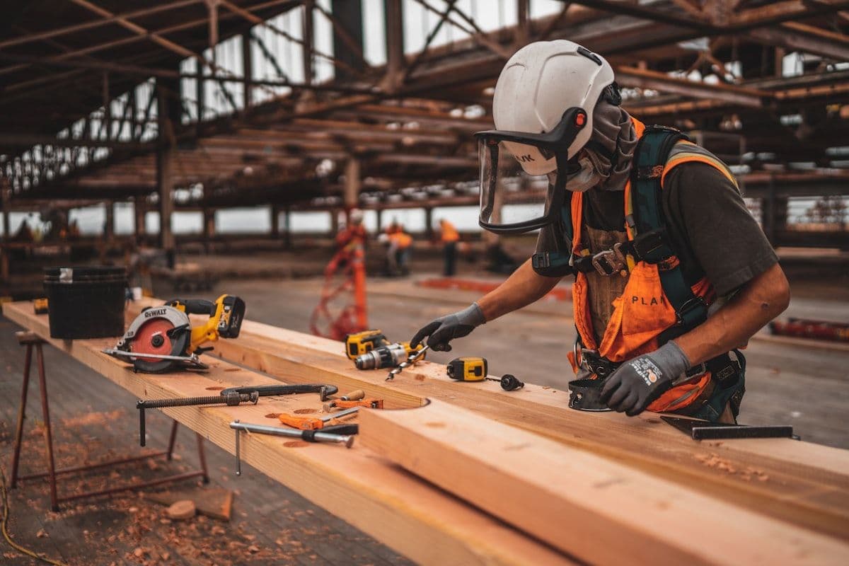 Artisan en tenue de travail tenant une perceuse électrique sur un chantier, représentant les artisans des Hautes-Alpes